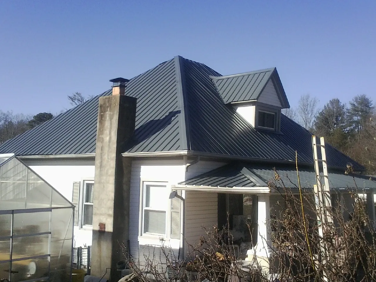 Dark blue standing seam metal roof on a white farmhouse with dormer — Slate & Tile Roof Repair by Roofing Brothers in Gnadenhutten