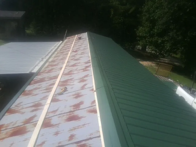 Old rusted panels beside newly installed green metal roofing — Wind Damage Roof Repair by Roofing Brothers in Gnadenhutten