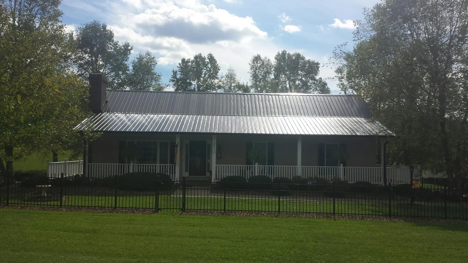 Gray metal roof on a brick ranch with a full width front porch — Gutter Guard Installation work by our crew in Gnadenhutten