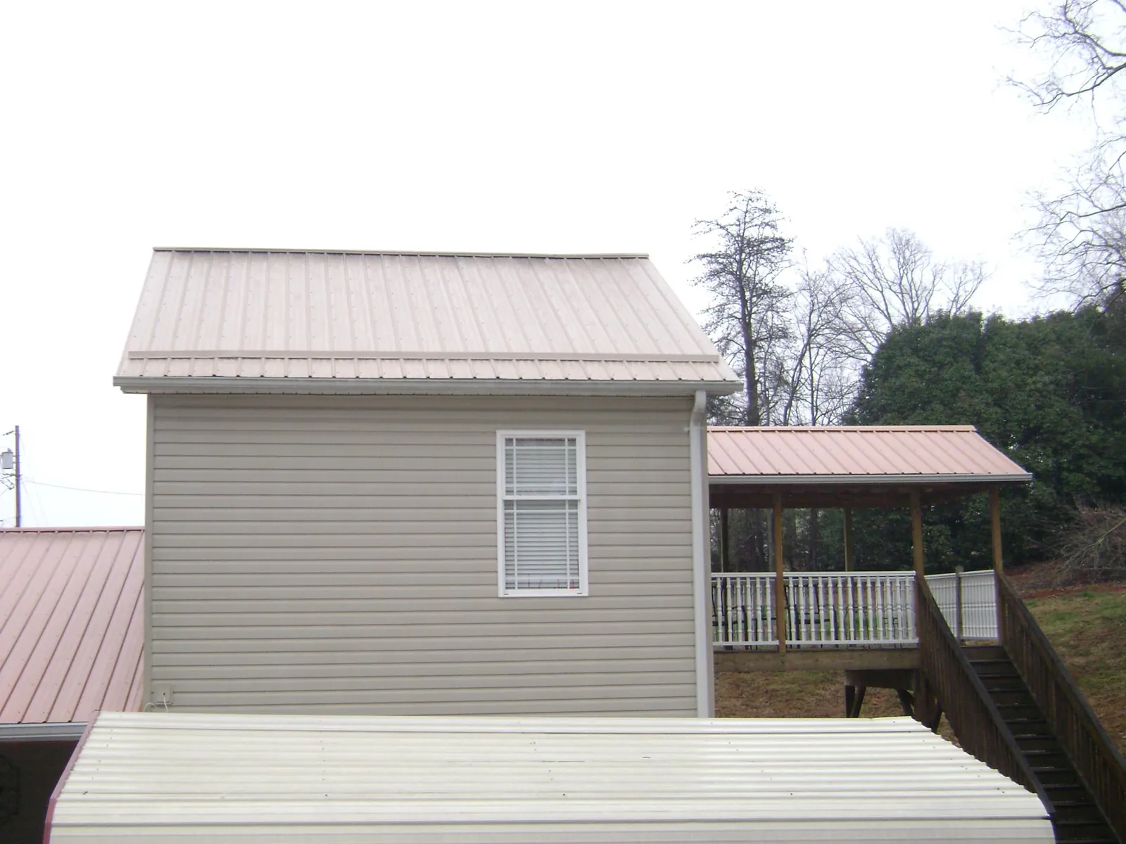 Tan metal roofs on a two story addition and attached porch, from a Roof Replacement job in Gnadenhutten