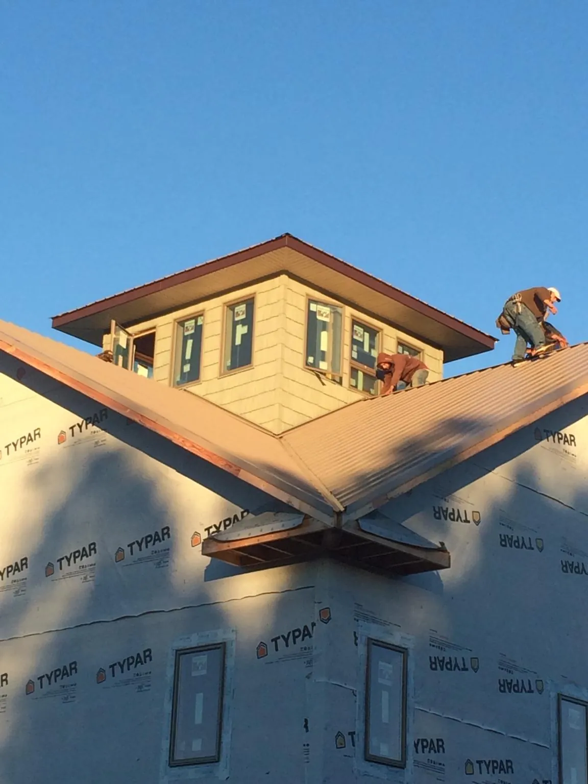 Roofers working around a rooftop cupola on a new metal roof at sunset — Roof Waterproofing in Gnadenhutten by Roofing Brothers